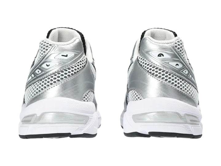 Tenis deportivos ASICS GEL-1130 color blanco y plateado con detalles negros y malla transpirable.