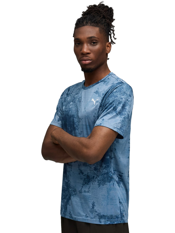 Hombre vistiendo playera deportiva Puma color azul con estampado abstracto.