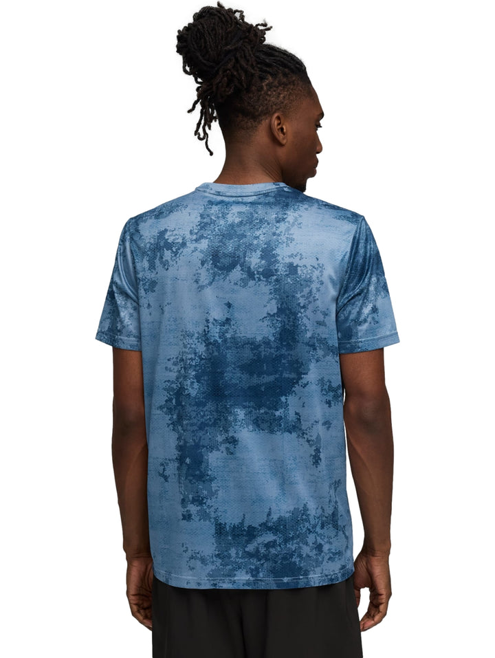 Hombre vistiendo playera deportiva Puma color azul con estampado abstracto.