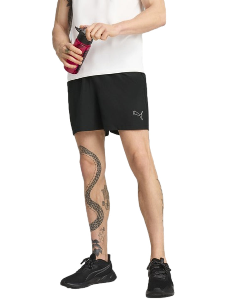 Hombre vistiendo shorts deportivos Puma de color negro y tenis negros.
