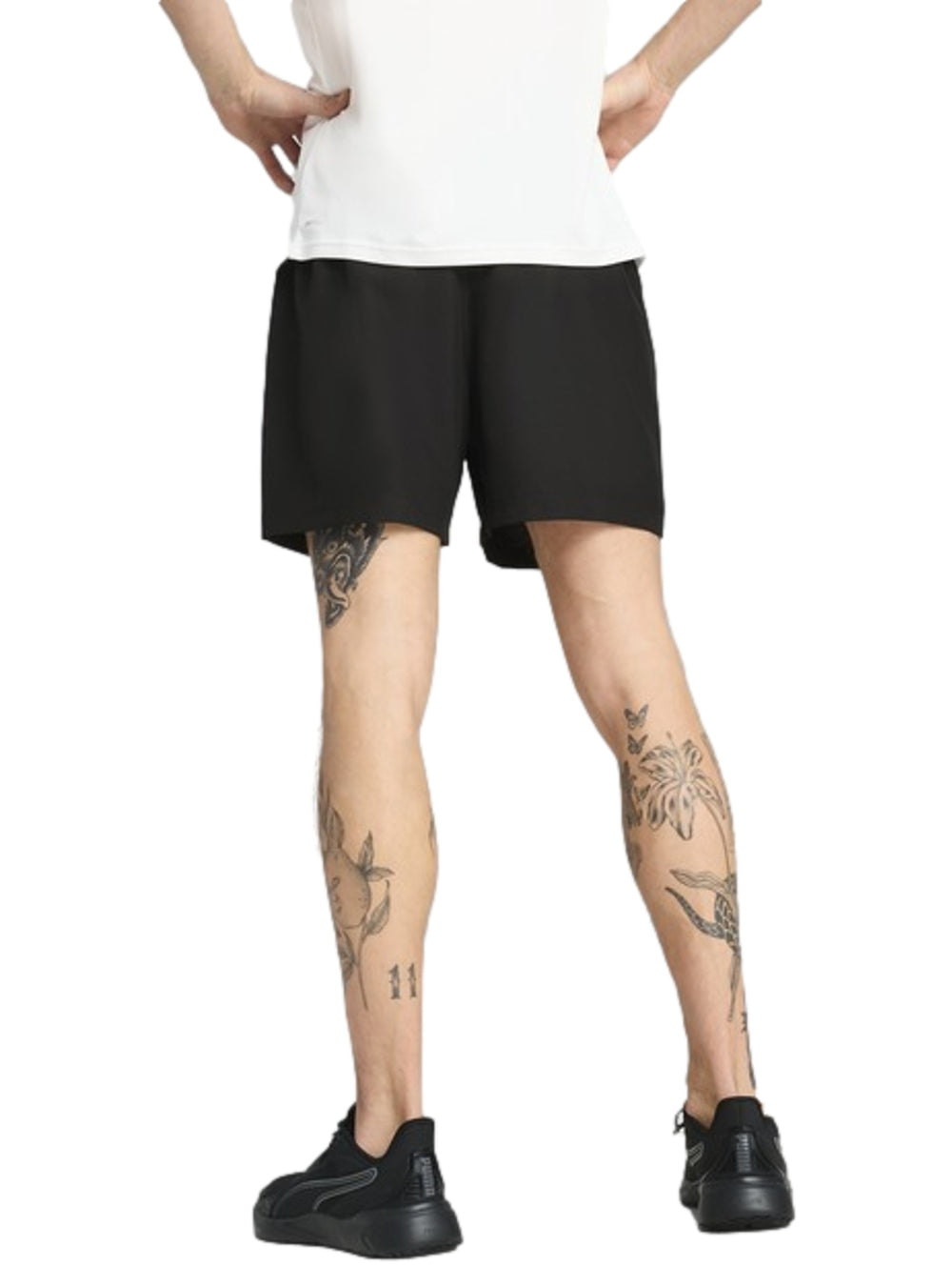 Hombre vistiendo shorts deportivos Puma de color negro y tenis negros.