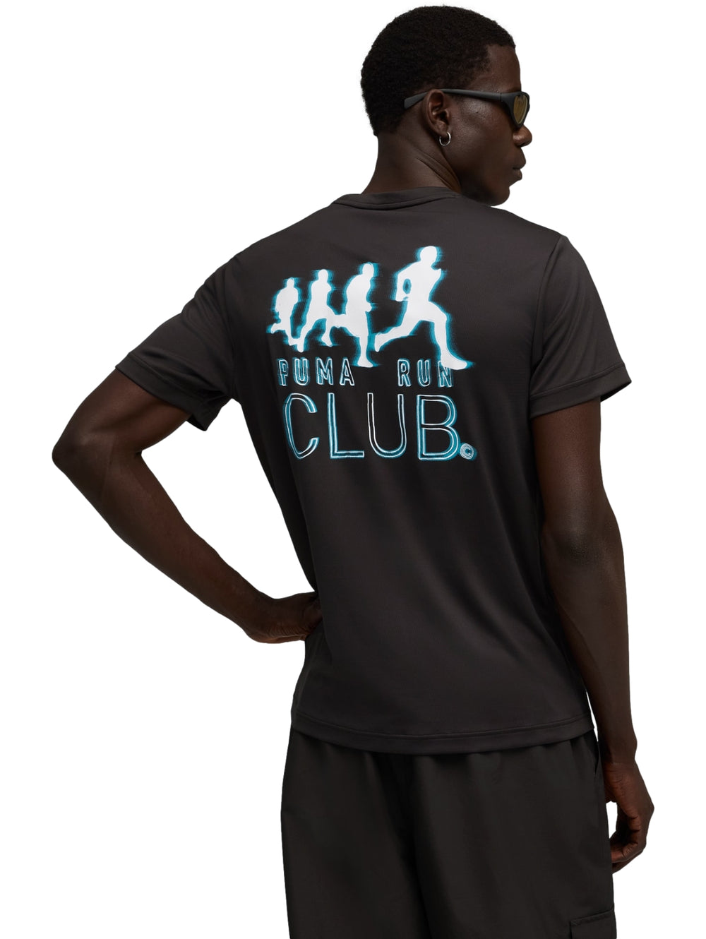 Hombre vistiendo playera deportiva Puma de color negro con gráfico pequeño en el pecho y shorts negros.