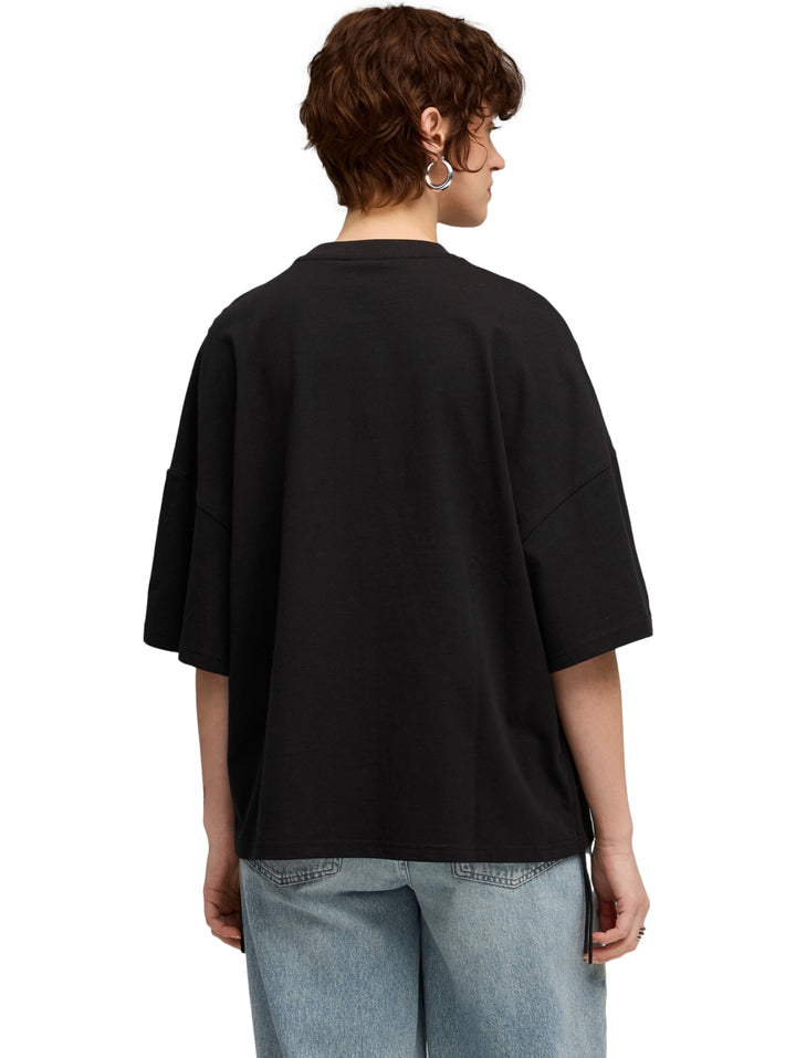 Mujer vistiendo una camiseta PUMA negra de corte oversized y cuello redondo.