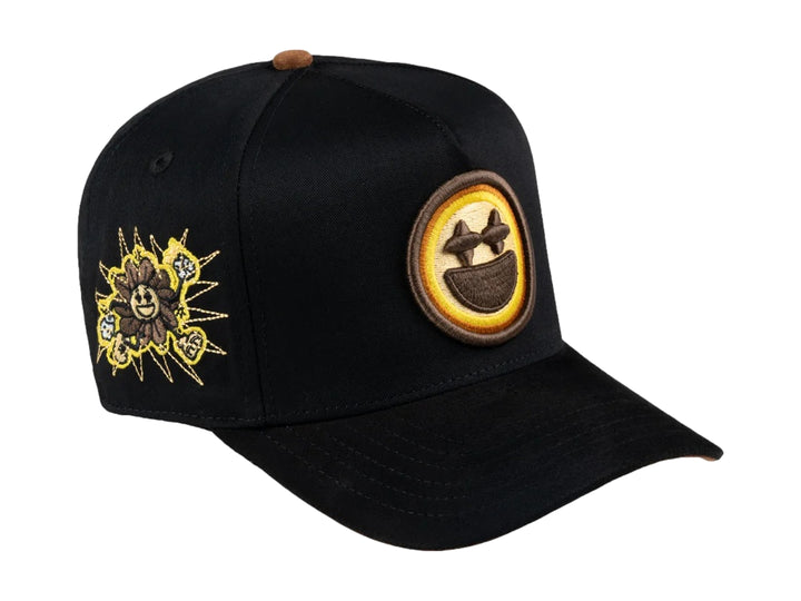 Gorra negra JC HATS con parche amarillo de carita feliz en el frente y detalle bordado lateral.
