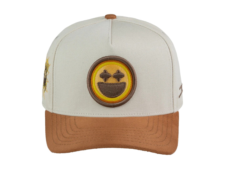 Gorra snapback color beige con visera marrón y un parche frontal de carita feliz amarilla.