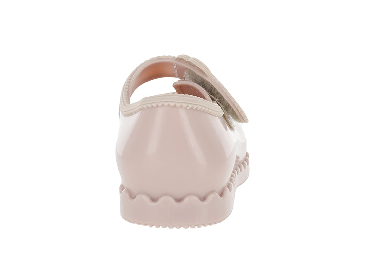 Zapato infantil Mini Melissa color rosa con adorno de flor y suela ondulada.