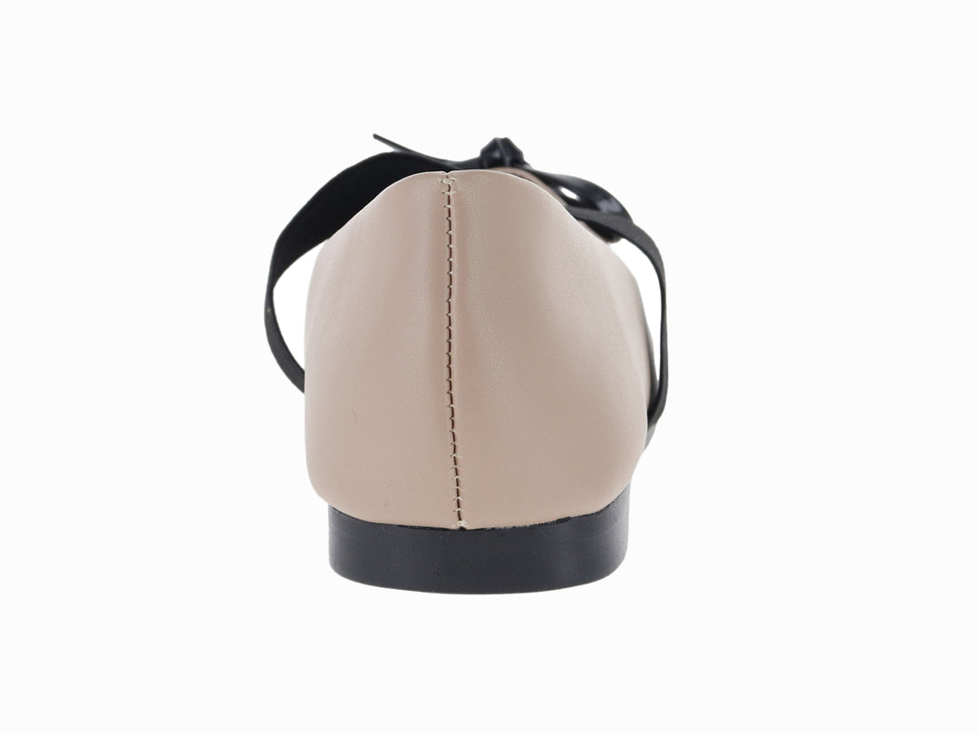 Zapato plano color beige con tira y moño decorativo en color negro.