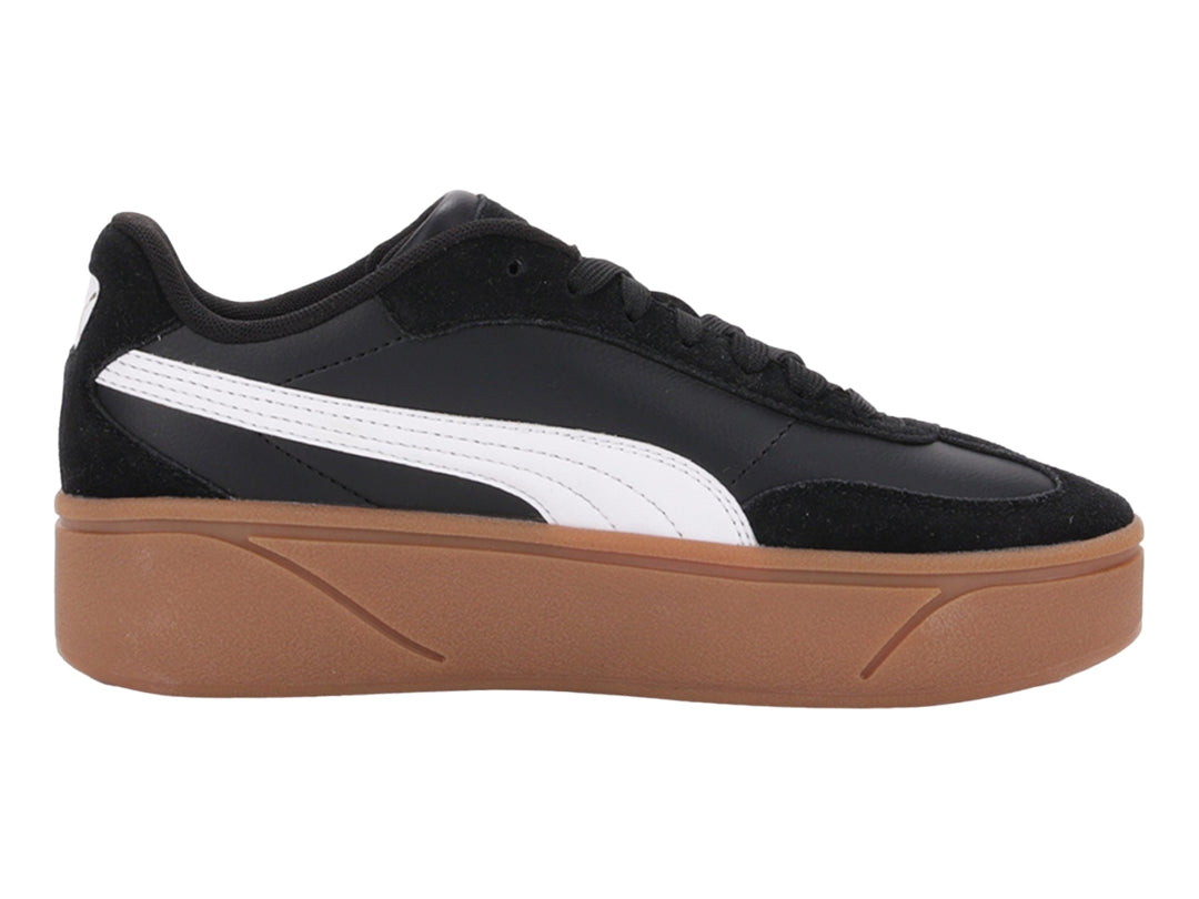 Tenis PUMA negros con suela de plataforma color goma y franja blanca lateral.
