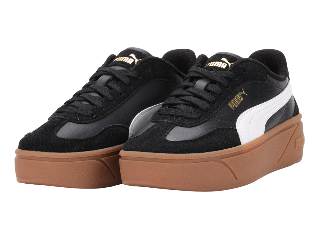 Tenis PUMA negros con suela de plataforma color goma y franja blanca lateral.