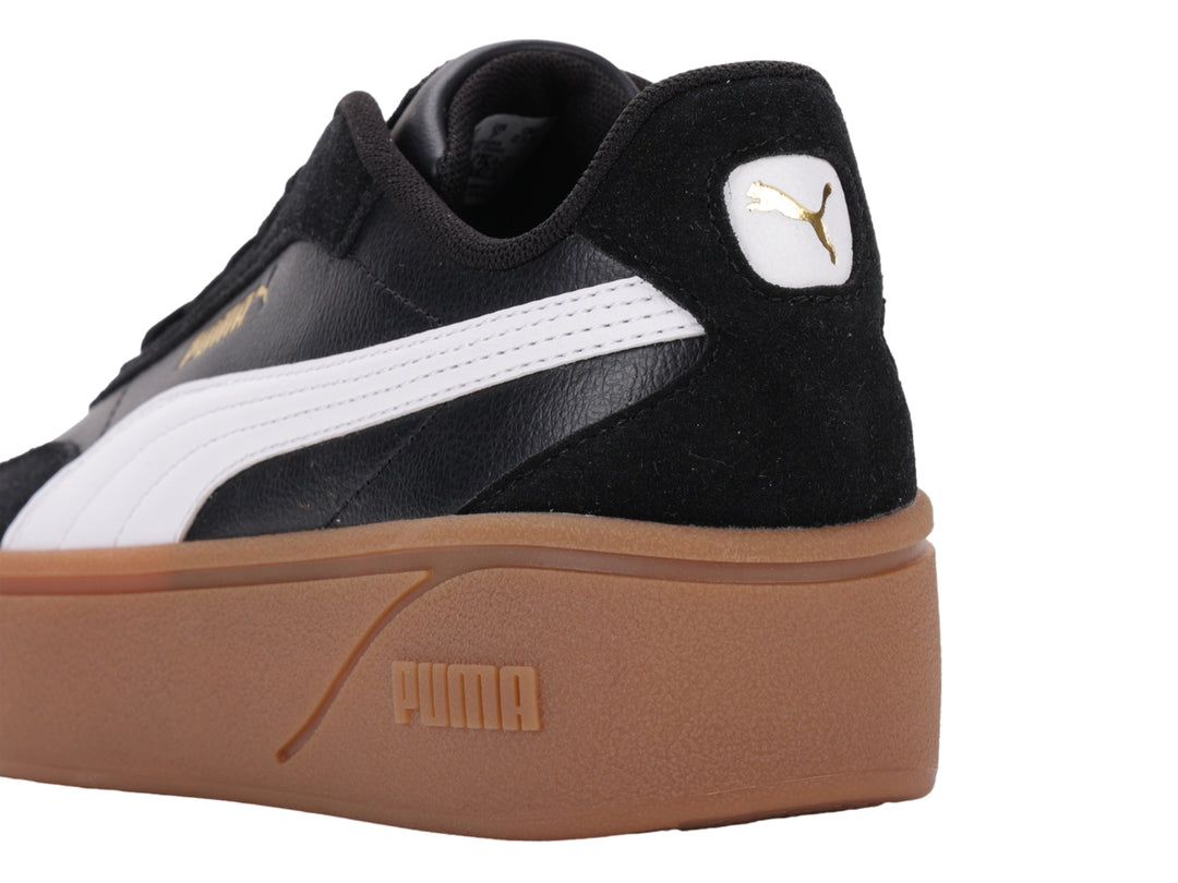 Tenis PUMA negros con suela de plataforma color goma y franja blanca lateral.