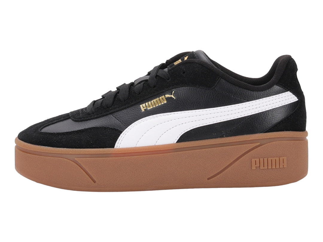 Tenis PUMA negros con suela de plataforma color goma y franja blanca lateral.
