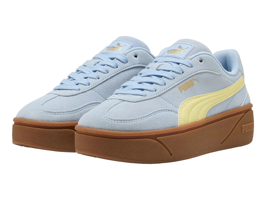 Tenis PUMA azul claro con franja amarilla y suela de plataforma marrón.
