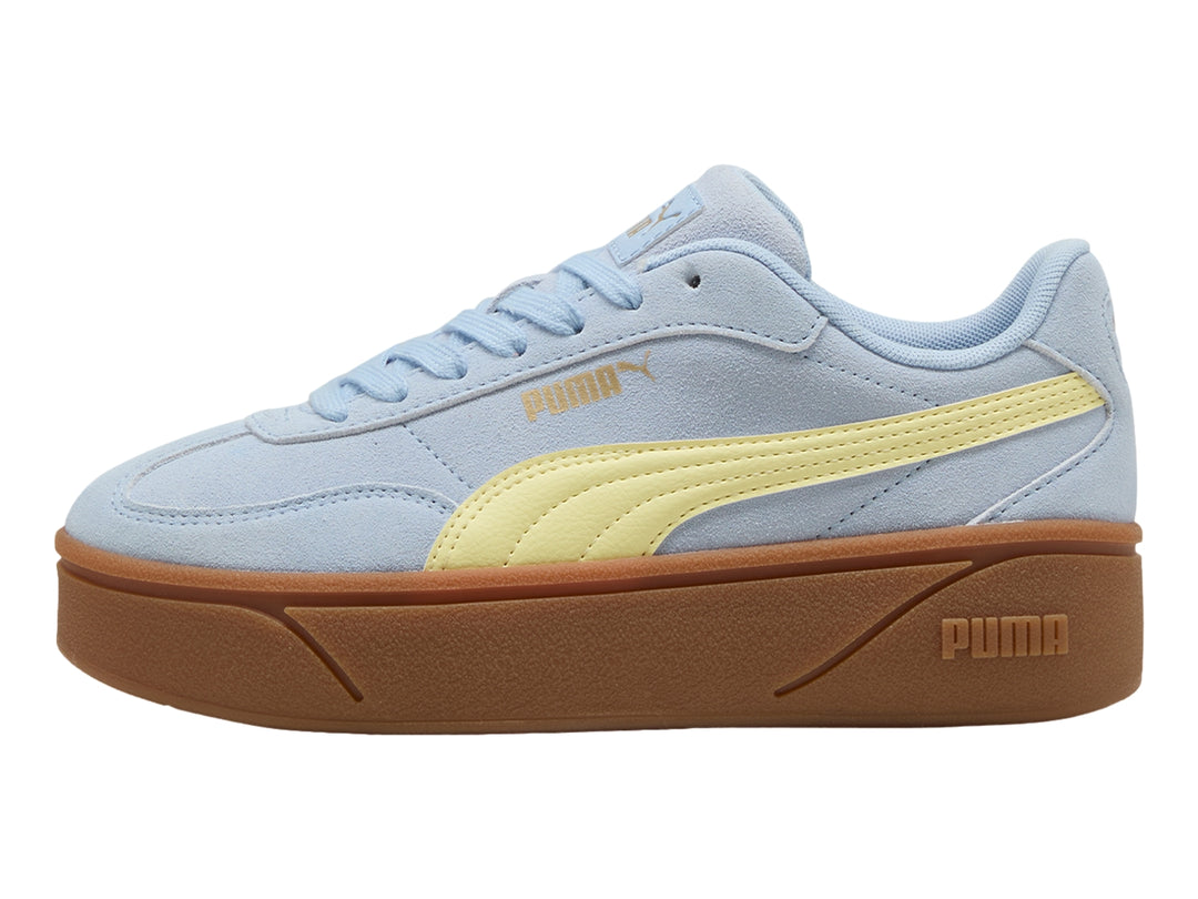 Tenis PUMA azul claro con franja amarilla y suela de plataforma marrón.