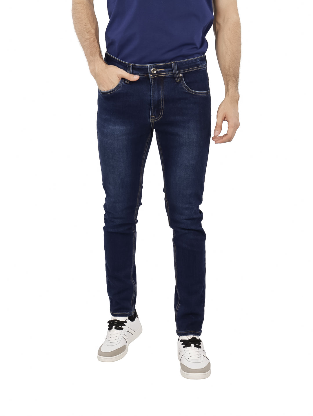 Hombre vistiendo pantalones jeans ajustados de color azul oscuro y tenis blancos.