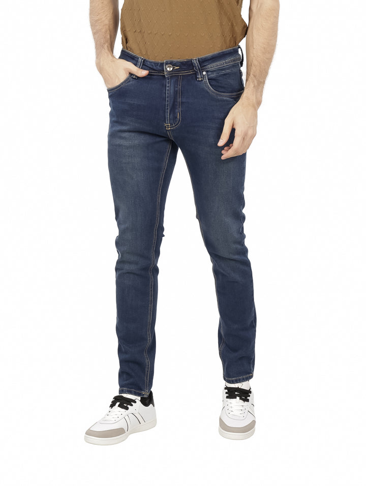 Hombre vistiendo pantalones jeans ajustados de color azul oscuro con costuras claras.