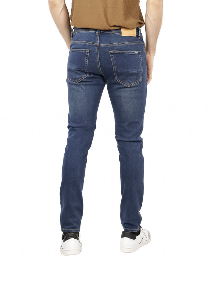 Hombre vistiendo pantalones jeans ajustados de color azul oscuro con costuras claras.
