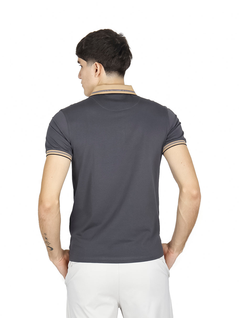 Hombre vistiendo playera polo color charcoal con detalles en beige en el cuello y puños de las mangas.