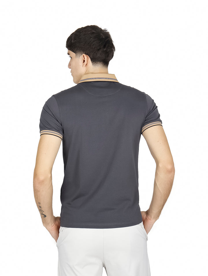 Hombre vistiendo playera polo color charcoal con detalles en beige en el cuello y puños de las mangas.