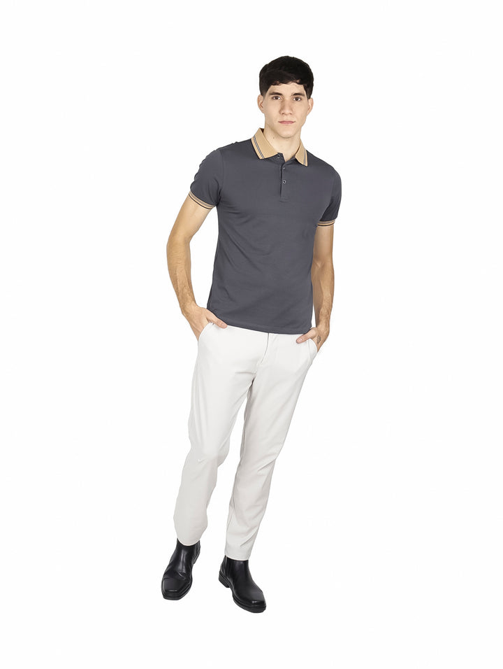 Hombre vistiendo playera polo color charcoal con detalles en beige en el cuello y puños de las mangas.