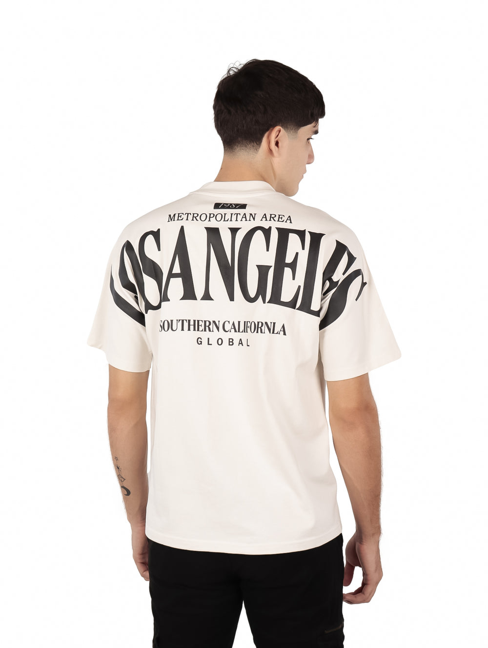 Hombre vistiendo playera oversize color beige con estampado de Los Angeles en el pecho.