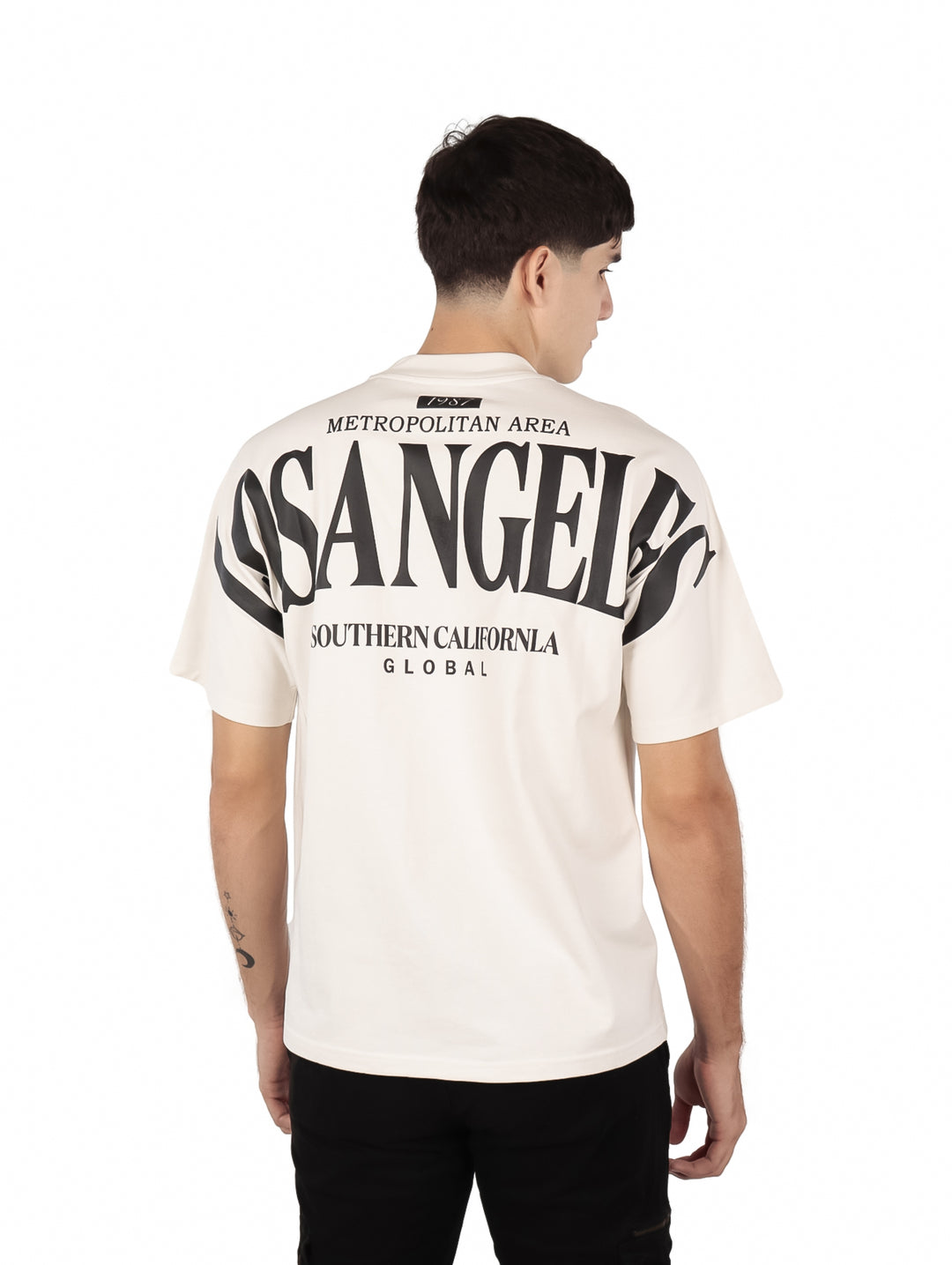 Hombre vistiendo playera oversize color beige con estampado de Los Angeles en el pecho.