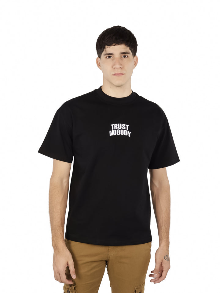 Hombre vistiendo playera oversize color negro con texto blanco &