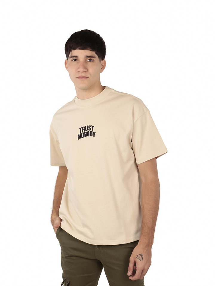 Hombre vistiendo una playera beige de manga corta con texto en el pecho.