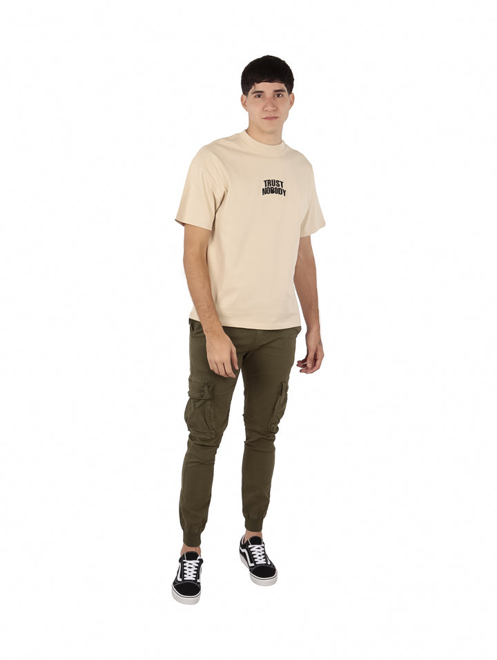 Hombre vistiendo una playera beige de manga corta con texto en el pecho.