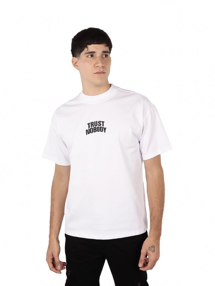 Hombre vistiendo una playera blanca oversize de manga corta con texto negro en el pecho.