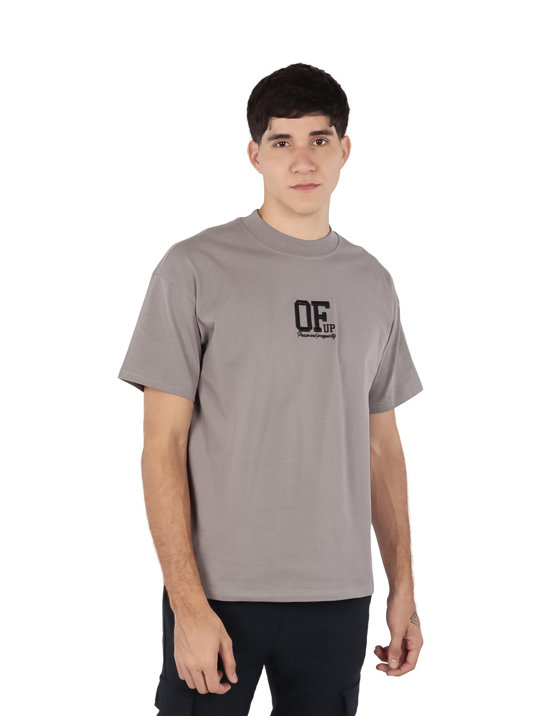 Hombre vistiendo una playera de manga corta color gris con un logotipo negro en el pecho.