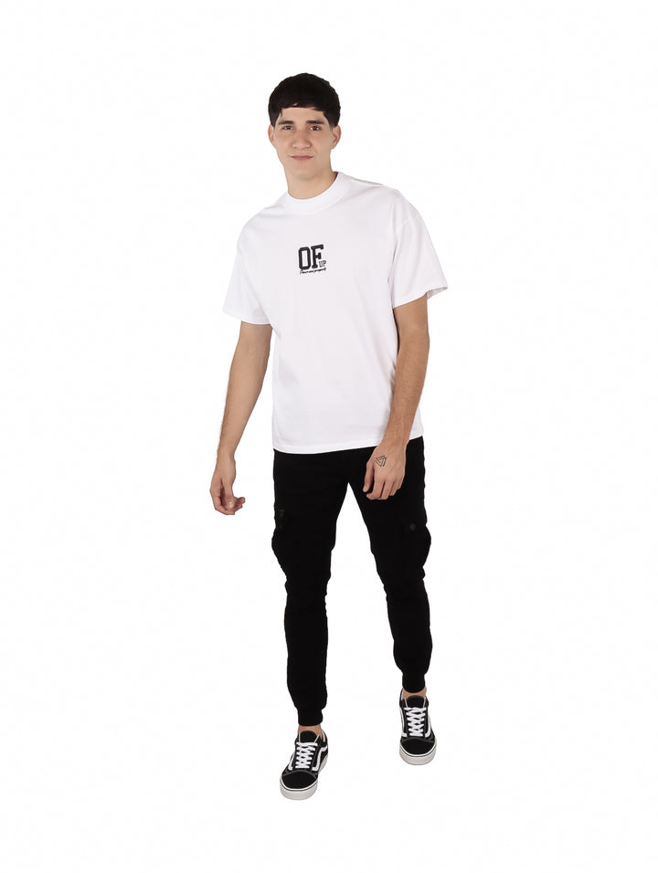 Hombre vistiendo una playera blanca oversize de manga corta con estampado negro en el pecho.