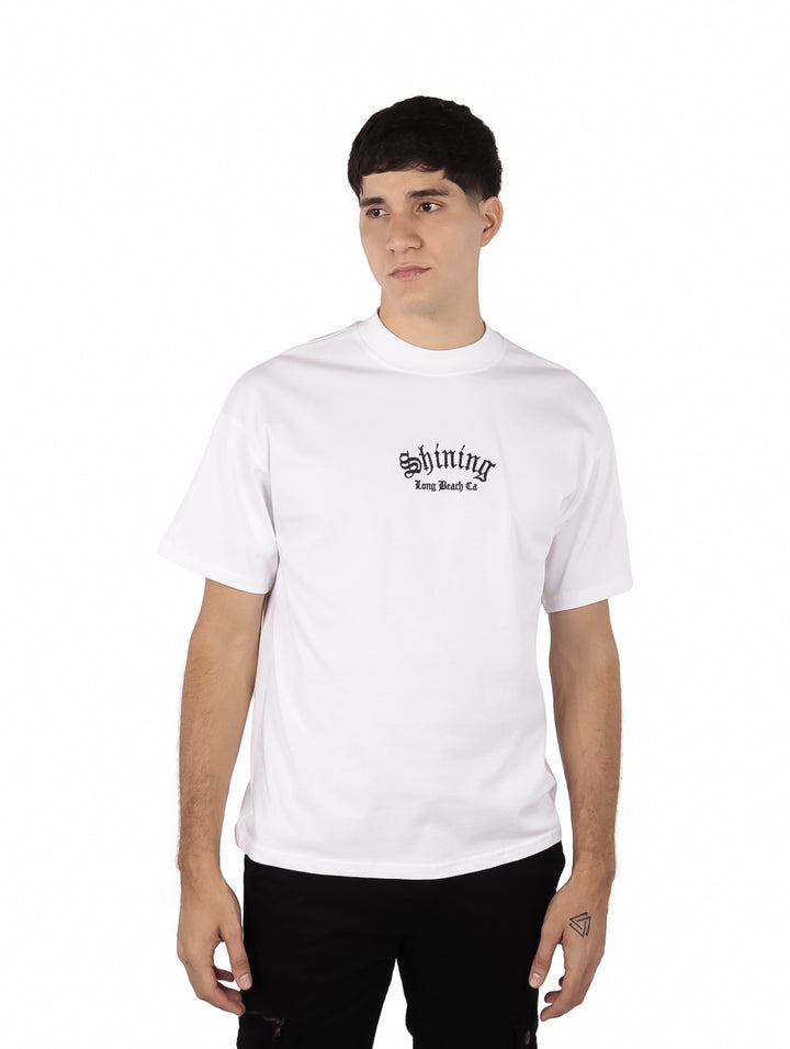 Hombre vistiendo playera blanca de manga corta con estampado negro en el pecho.