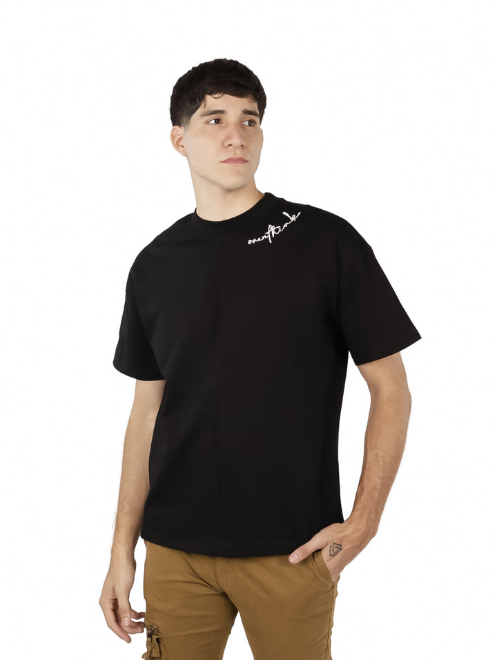 Hombre vistiendo playera negra de manga corta con detalle de texto blanco en el área del cuello.