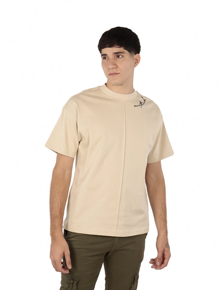 Hombre vistiendo playera oversize color beige de manga corta y cuello redondo.