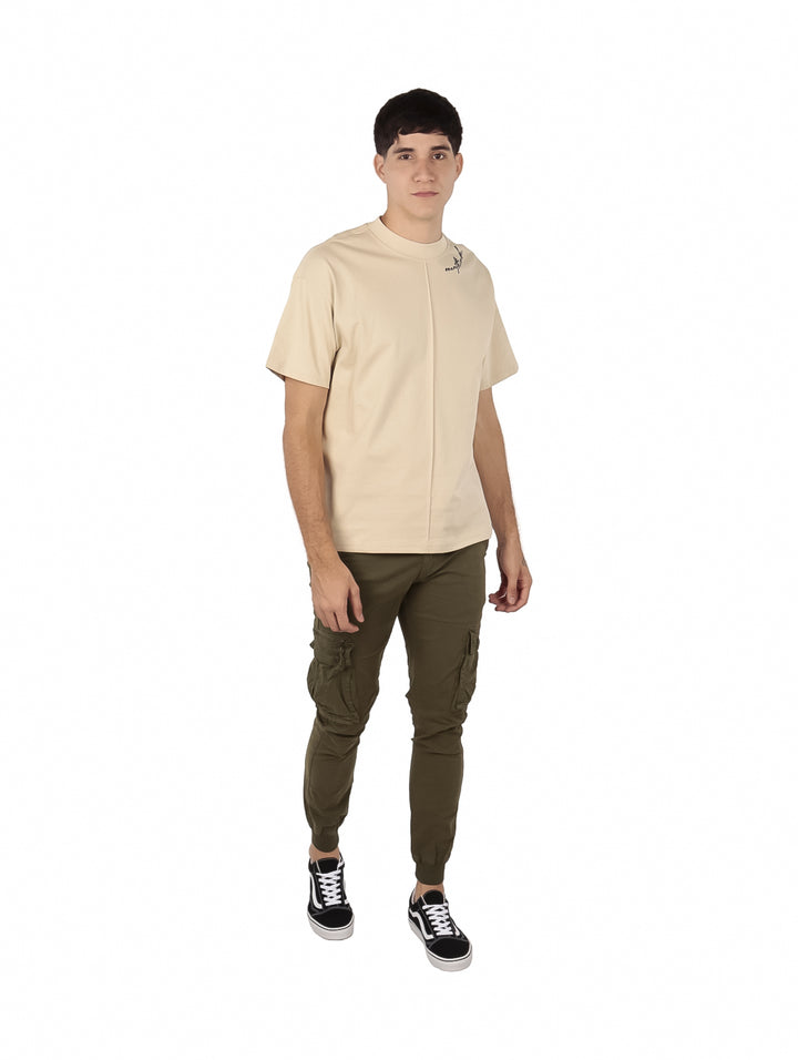 Hombre vistiendo playera oversize color beige de manga corta y cuello redondo.