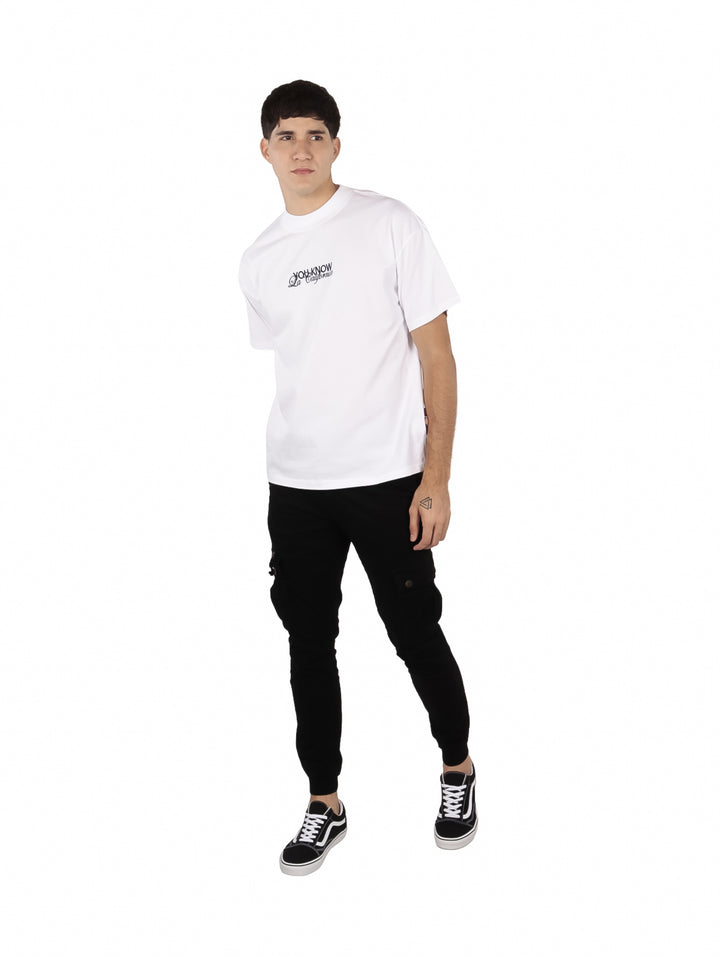 Hombre vistiendo una playera blanca oversize de manga corta con un pequeño estampado negro en el pecho.