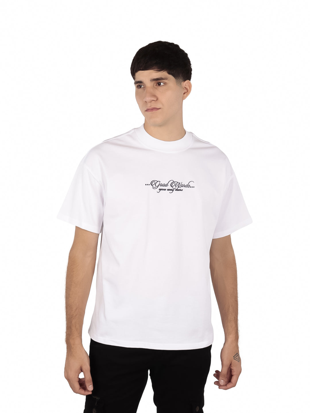 Hombre vistiendo playera oversize color blanco con un pequeño estampado de texto en el pecho.
