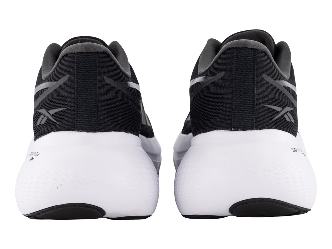 Tenis deportivos Reebok color negro con suela blanca y detalles laterales en gris.