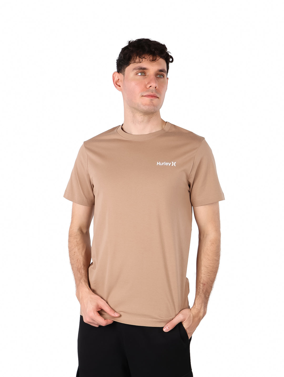 Hombre vistiendo una camiseta de manga corta color beige marca Hurley con logotipo pequeño en el pecho.