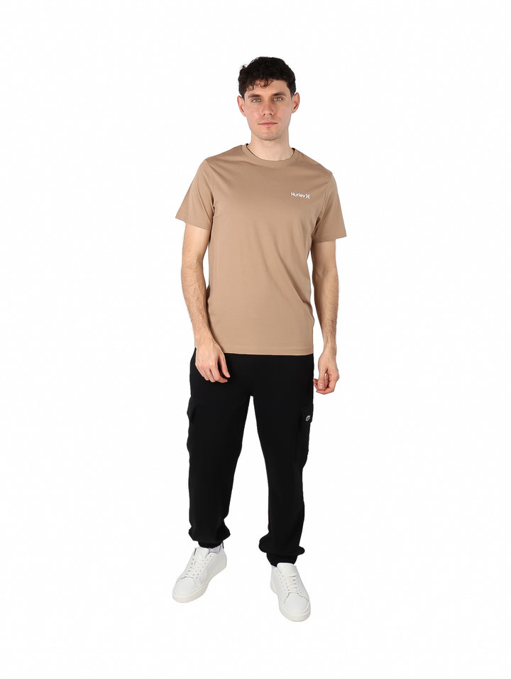 Hombre vistiendo una camiseta de manga corta color beige marca Hurley con logotipo pequeño en el pecho.