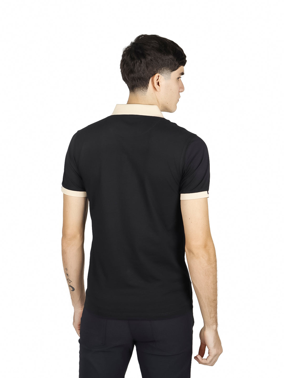 Hombre vistiendo playera polo negra con cuello y puños beige y un detalle de línea roja en el cuello.
