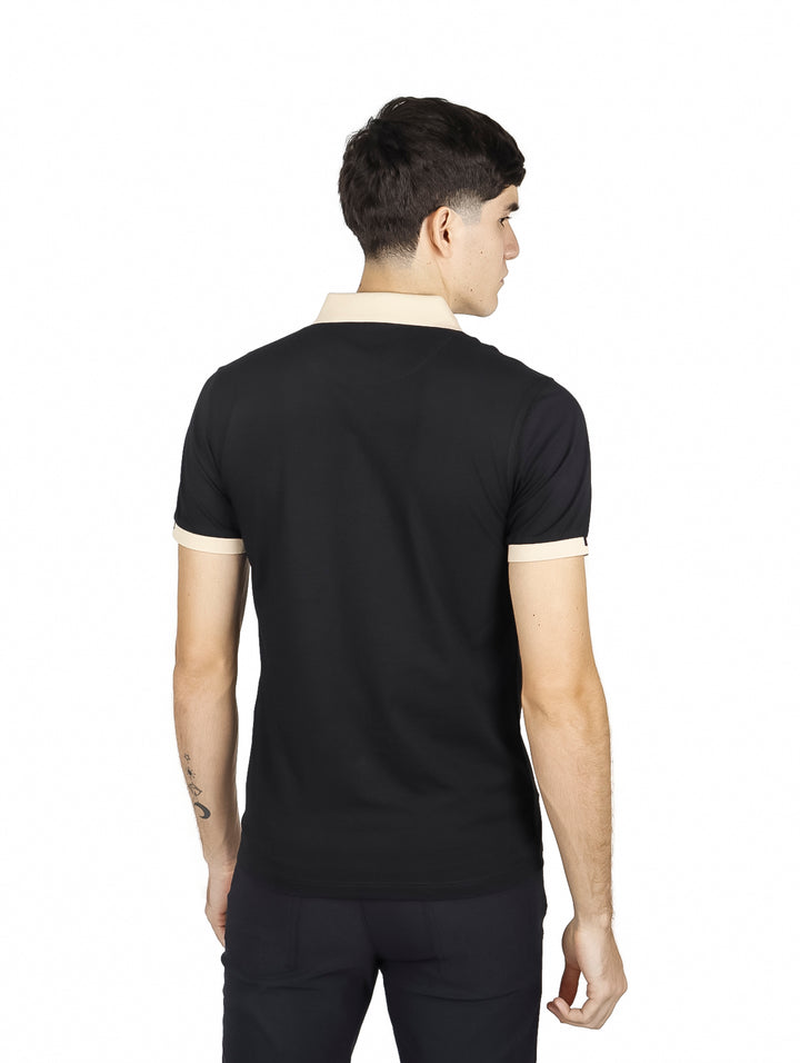Hombre vistiendo playera polo negra con cuello y puños beige y un detalle de línea roja en el cuello.