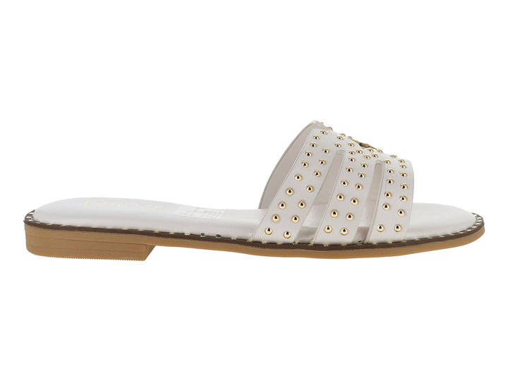 Sandalia plana color off white para mujer con tiras decoradas con tachuelas doradas y suela café.
