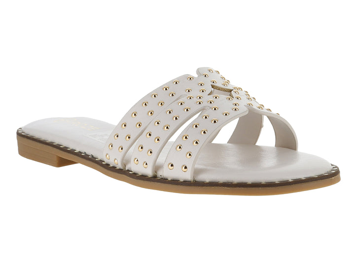 Sandalia plana color off white para mujer con tiras decoradas con tachuelas doradas y suela café.
