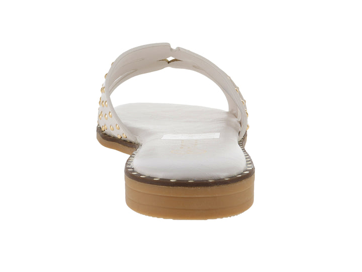 Sandalia plana color off white para mujer con tiras decoradas con tachuelas doradas y suela café.