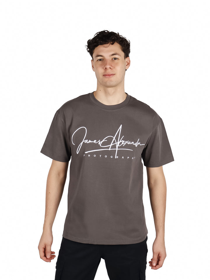 Hombre vistiendo playera gris oscuro de corte oversize con estampado blanco en el pecho.