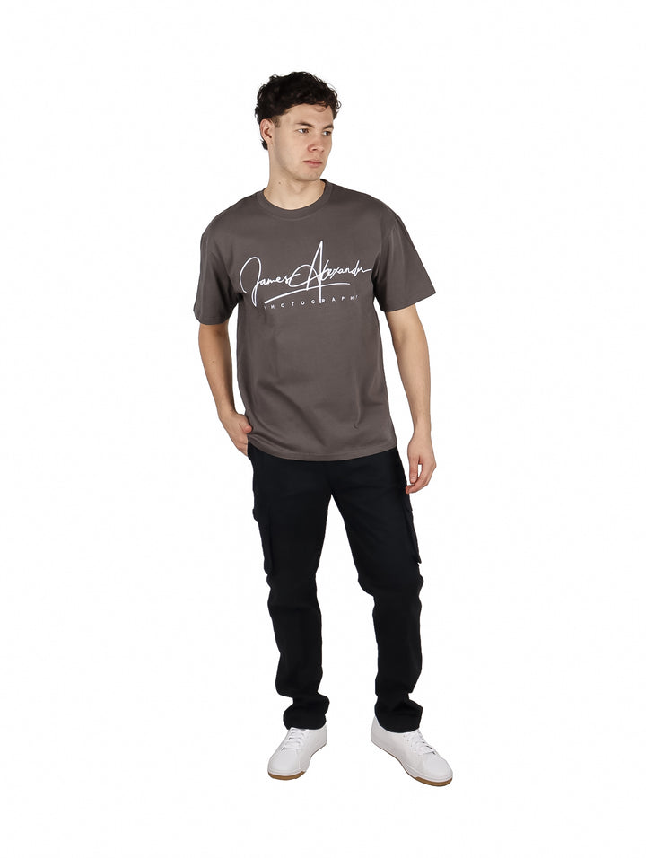 Hombre vistiendo playera gris oscuro de corte oversize con estampado blanco en el pecho.