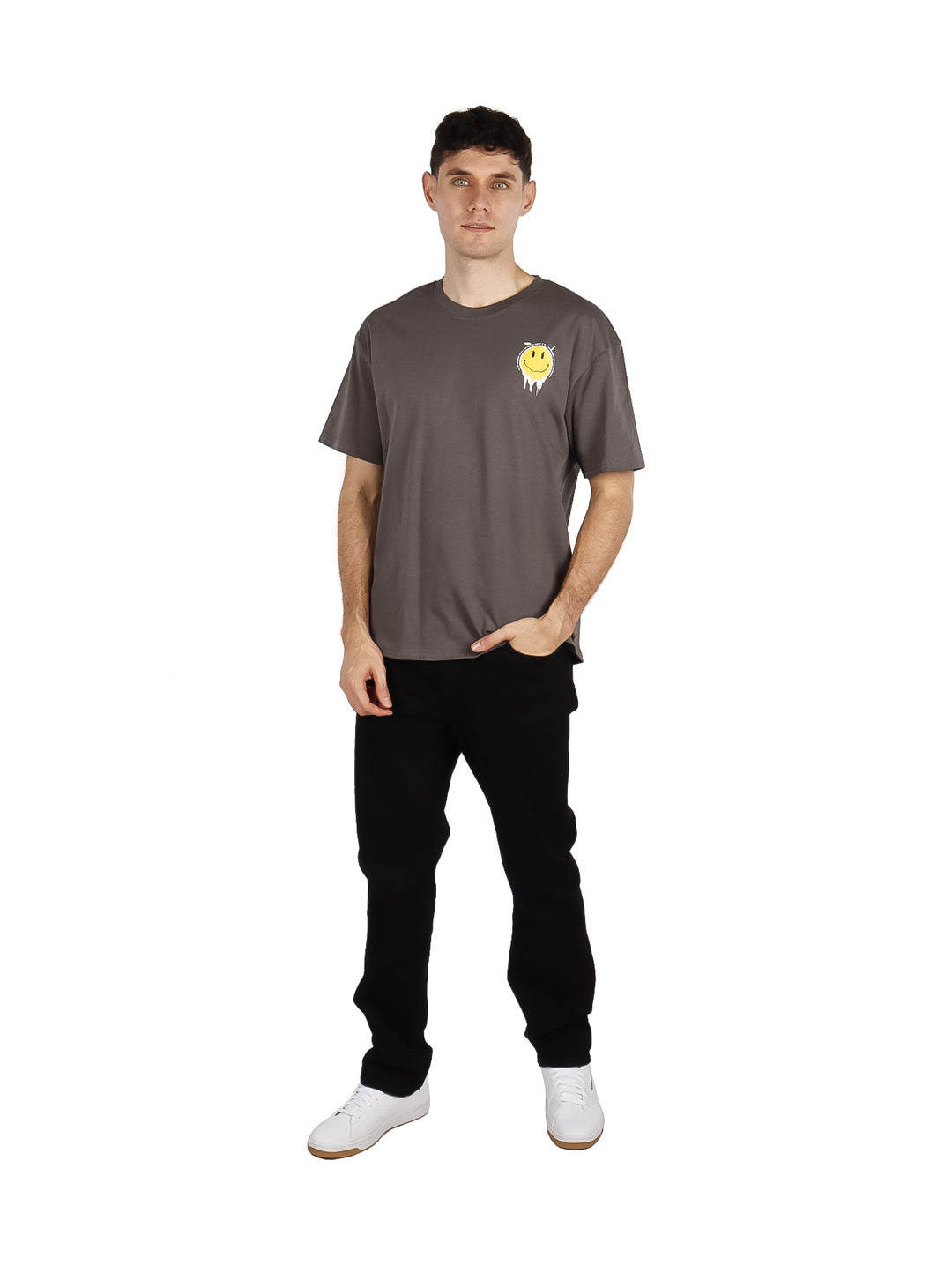Hombre vistiendo playera oversize color gris con un pequeño gráfico de cara sonriente amarilla en el pecho.
