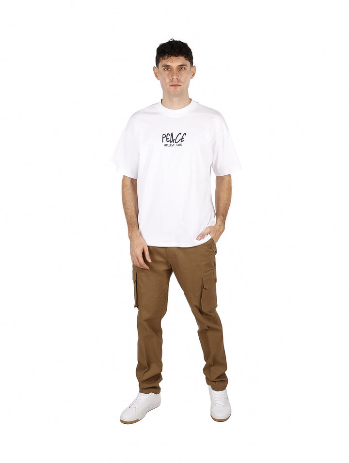 Hombre vistiendo playera blanca oversize de manga corta con estampado negro en el pecho.