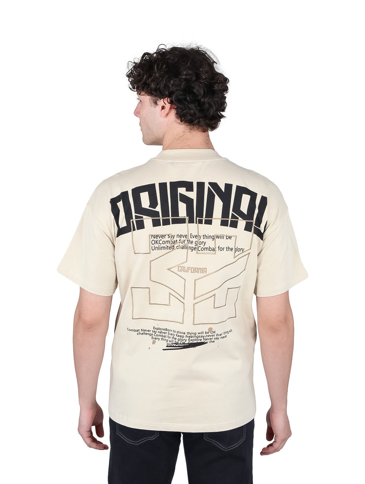 Hombre vistiendo playera oversize color beige con estampado negro en el pecho.